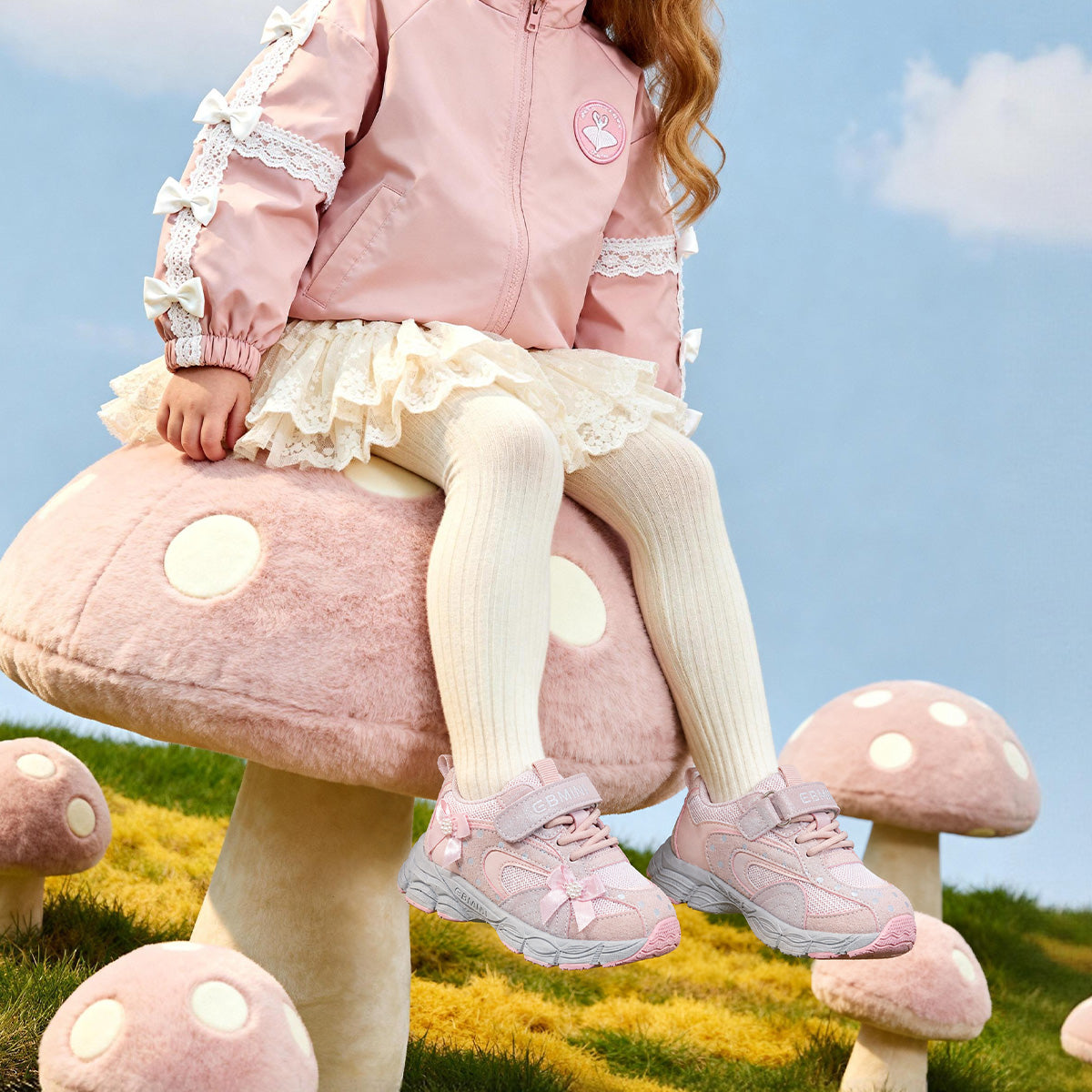 Girl wearing pink EBMINI PEARL bow sneakers in a playful princess setting