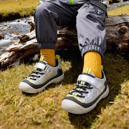 Child wearing silver EBMINI RIDGE protective sneakers on a rocky trail
