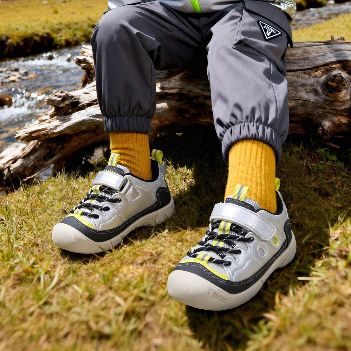 Child wearing silver EBMINI RIDGE protective sneakers on a rocky trail