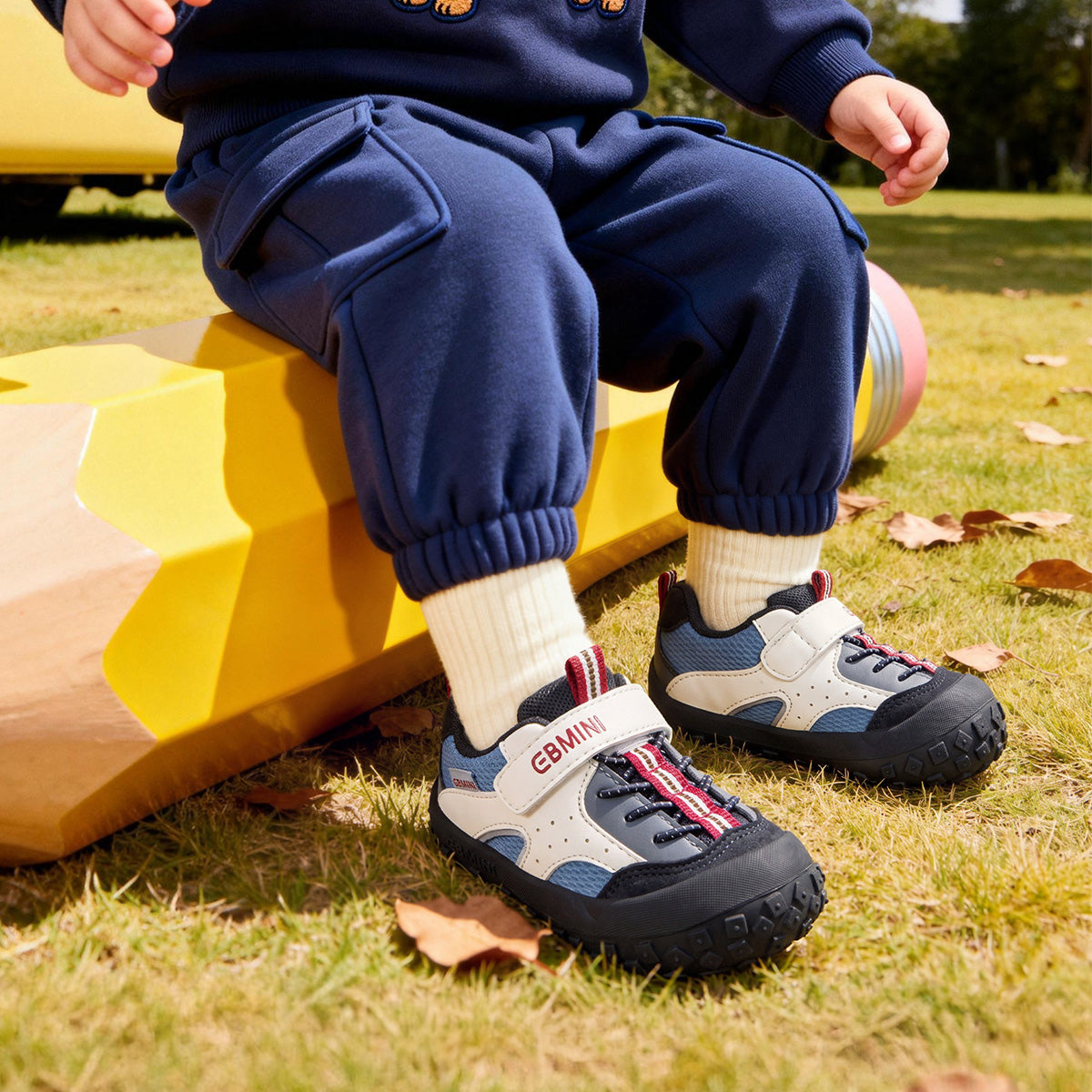 Child wearing black EBMINI ROVER toddler sneakers in a park